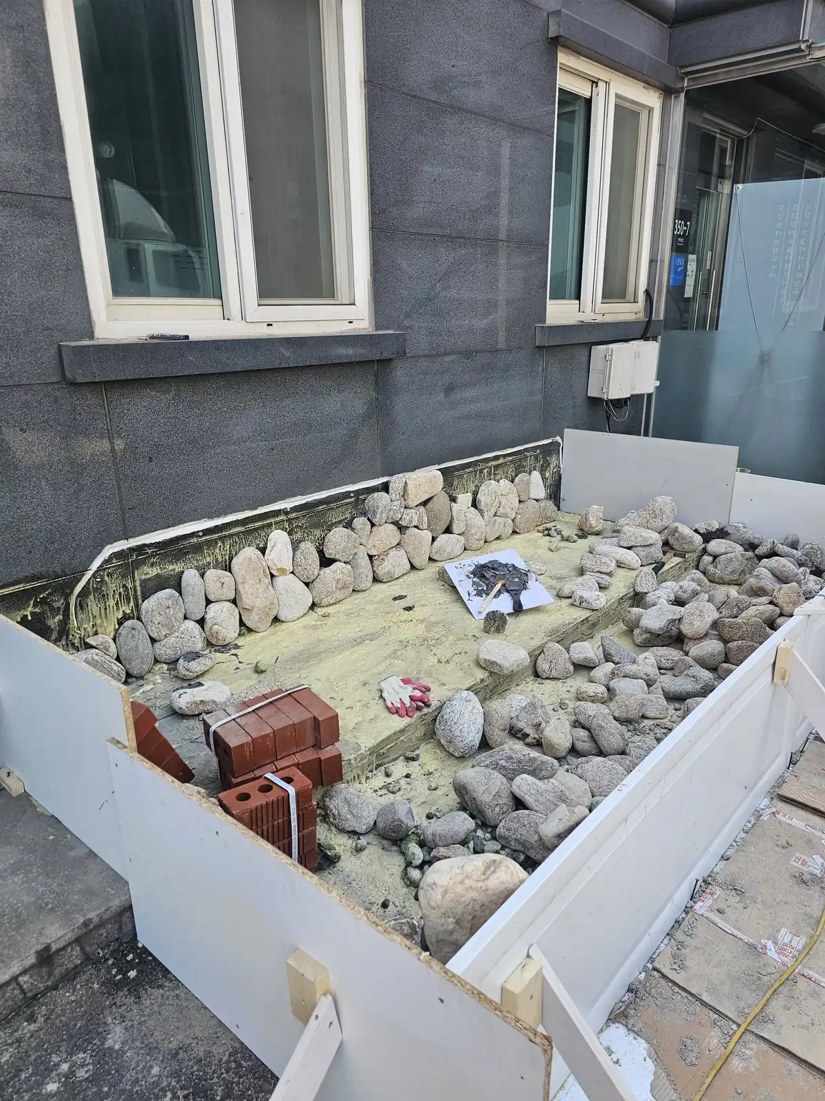 건물 입구 연못 리모델링 중 거푸집 안쪽 돌 붙임